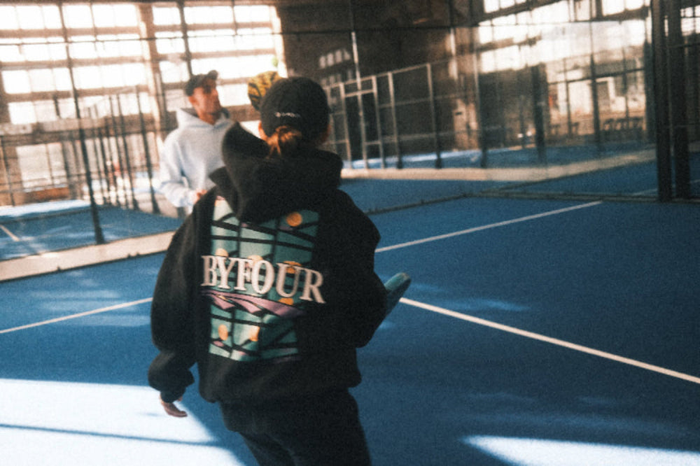 Two players in Byfour Padel clothing passing a bll on court